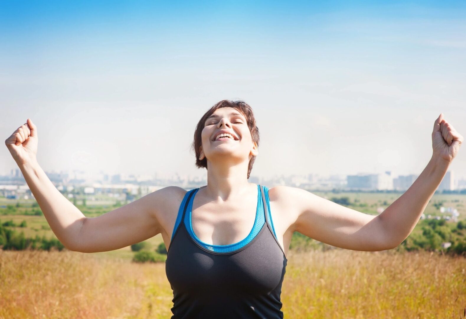 A woman with her arms outstretched in the middle of a field.